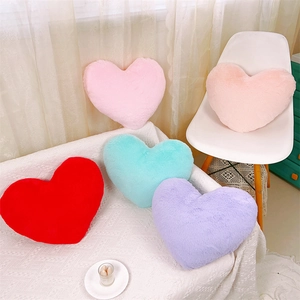 Coussins en peluche en forme de cœur en cinq couleurs sur un canapé de salon