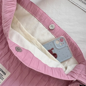 Detail view of pink pleated tote bag interior with magnetic closure and canvas lining