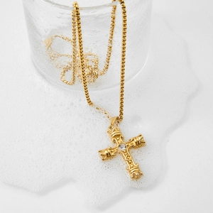 Luxury gold 3D cross pendant necklace with clear gemstone in a glass display