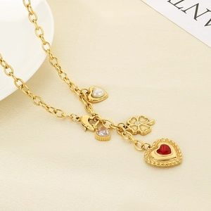 Macro view of gold-tone necklace with red heart gemstone and clover leaf charms