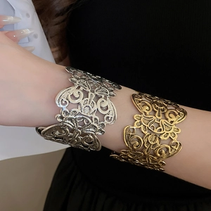 Detail of vintage hollow flower wide open metal bangle in gold and silver finish