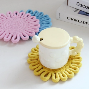 Detailed view of woven flower coasters in yellow, pink and blue cotton rope