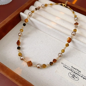 Detail of amber geometric beads and faux pearls on a vintage beaded necklace