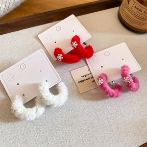Detailed close-up of winter velvet snowflake C-shaped earrings in red, white and pink