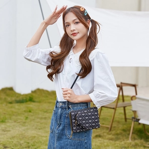 Crossbody phone bag with heart prints worn by model in an outdoor park setting