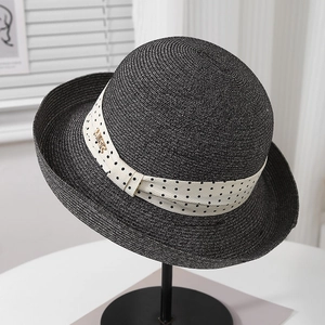 Close-up of black straw hat with white polka dot ribbon and gold MISS lettering