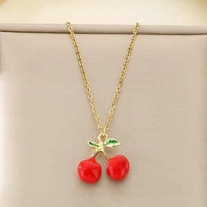 Detailed close-up of a gold cherry pendant necklace with red enamel on a jewelry stand