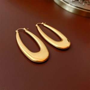Detailed view of gold U-shaped metal hoop earrings with mirror polished finish
