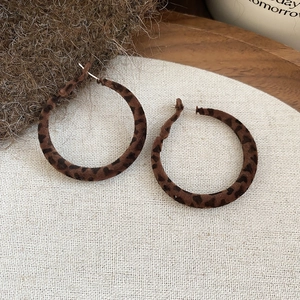 Gros plan sur des créoles vintage floquées à motif léopard sur fond de tissu beige