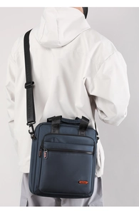 Detail of navy blue nylon messenger bag with multiple zipper pockets shown on model back