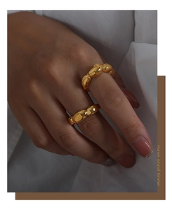 Detailed view of chunky gold chain-link rings worn on fingers with a polished mirror finish