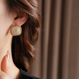 Close-up of square gold-plated stud earrings featuring micro-pave white cubic zirconia stones