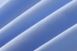 Macro shot of light blue combed cotton fabric showing fine weave texture and soft folds