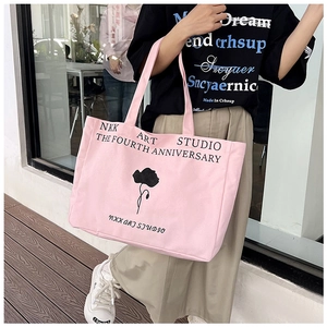 Detail of pink canvas tote bag with black floral print and stylish letter design