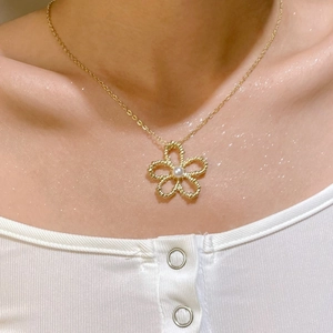 Close-up of golden fine chain necklace featuring a hollow flower pendant with central pearl