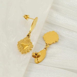 Boucles d'oreilles vintage en forme de cœur doré avec relief sur tissu blanc