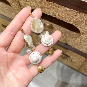 Detail of seashell drop earrings with pearls and golden pendants for vacation
