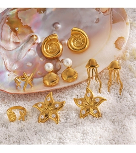 Collection of golden starfish shells and pearl jewelry displayed on sea sand