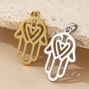 Macro shot of gold and silver hollow Hamsa Hand pendants with heart design on stone