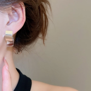 Detailed close-up of rectangular double-layered silver stud earrings on a model