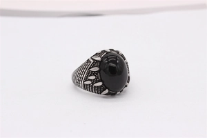 Détail d'une bague vintage avec pierre noire ovale et gravures de feuilles sur l'acier