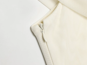 Detail of hidden zipper on white mesh paneled dress with fine fabric texture