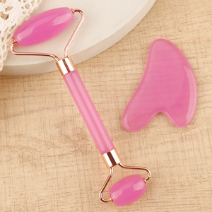 Detailed view of pink resin facial roller and heart-shaped gua sha set on a stone stand