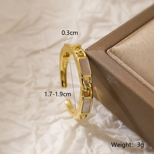 Macro detail of gold plated geometric ring with pink inlays on brown velvet box