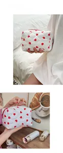 Close-up of white quilted cosmetic bag with red heart prints and a red zipper closure