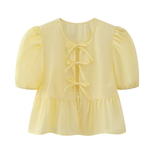 Detail of light yellow puff sleeve top with front tie-up bows and ruffled hem detail