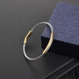 Close-up of stainless steel cable bracelet showing silver twisted wire and gold clasps