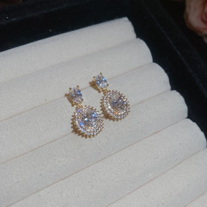 Macro view of gold-tone earrings with oval zircon stones in a velvet jewelry box