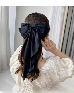 Detail showing oversized black satin ribbon hair bow with elegant long trailing tails