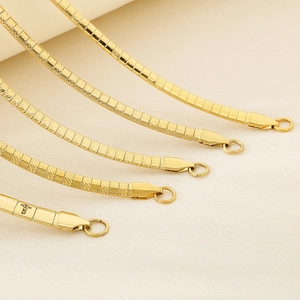 Detailed close-up of golden stainless steel flat snake chain necklace with textured surface