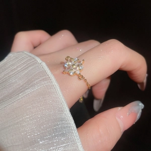 Exquisiter Goldkettenring mit Zirkon-Blumenanhänger am Modellfinger auf schwarzem Hintergrund