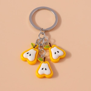 Macro shot of three miniature yellow pear keychains on a silver chain over pink background