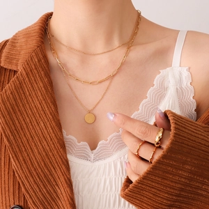 Three-layer gold pendant necklace with engraved round tag and link chains on model