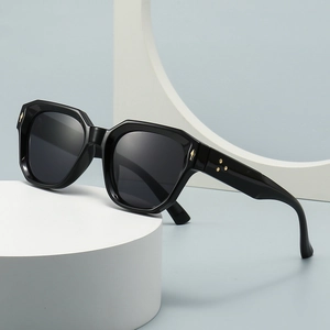 Retro schwarze geometrische Sonnenbrille mit goldenen Sternnieten auf weißer Säule