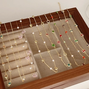 Detailed view of assorted gold chain bracelets with colorful zircon charms in a jewelry box