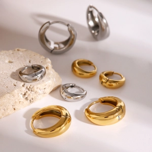 Detailed view of mixed size gold and silver stainless steel hoop earrings on stone display