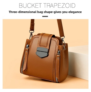 Detail of brown leather trapezoid bucket bag with metal buckle and herringbone stitching