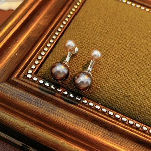 Détail macro de boucles d'oreilles vintage en perles champagne et chocolat sur velours brun