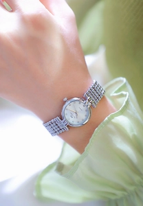 Close-up of elegant women's watch with green dial and silver band worn on wrist