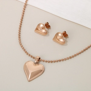 Macro detail of rose gold heart necklace and earrings set with elegant bead chain