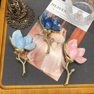 Elegant floral enamel brooches in blue and pink with gold metal stems on vintage background