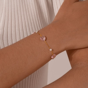 Detailed shot of kids' gold-plated bracelet with pink hearts and white pearls on wrist