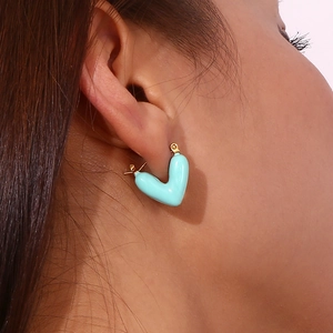 Close-up of a model wearing a light blue hollow heart earring in 18K gold plated steel