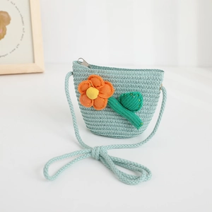 Detailed view of a cute mint green straw crossbody bag featuring a knit orange flower