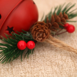 Close-up of a red metal Christmas bell featuring pine cones and vibrant red berries