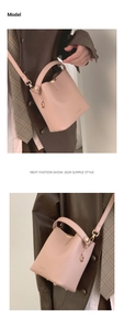 Detail view of pink bucket bag with top handle and adjustable strap on a female model